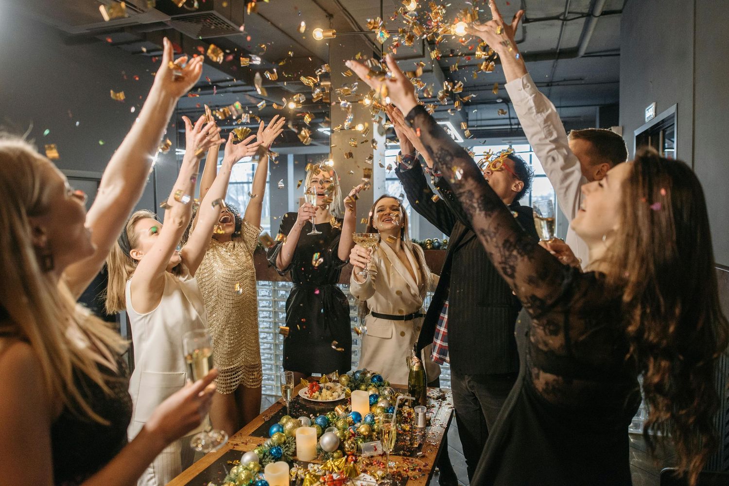 People celebrating at a lively indoor party with sparklers and raised hands creating a festive atmosphere.
