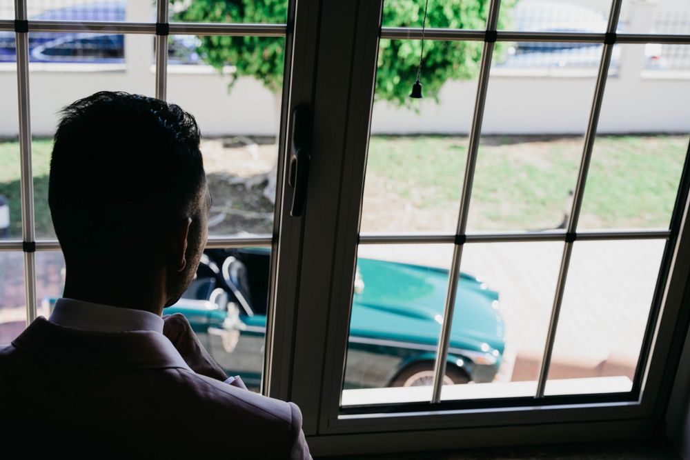 Yellow school bus drives past a residential area while children watch through classroom windows during school day.