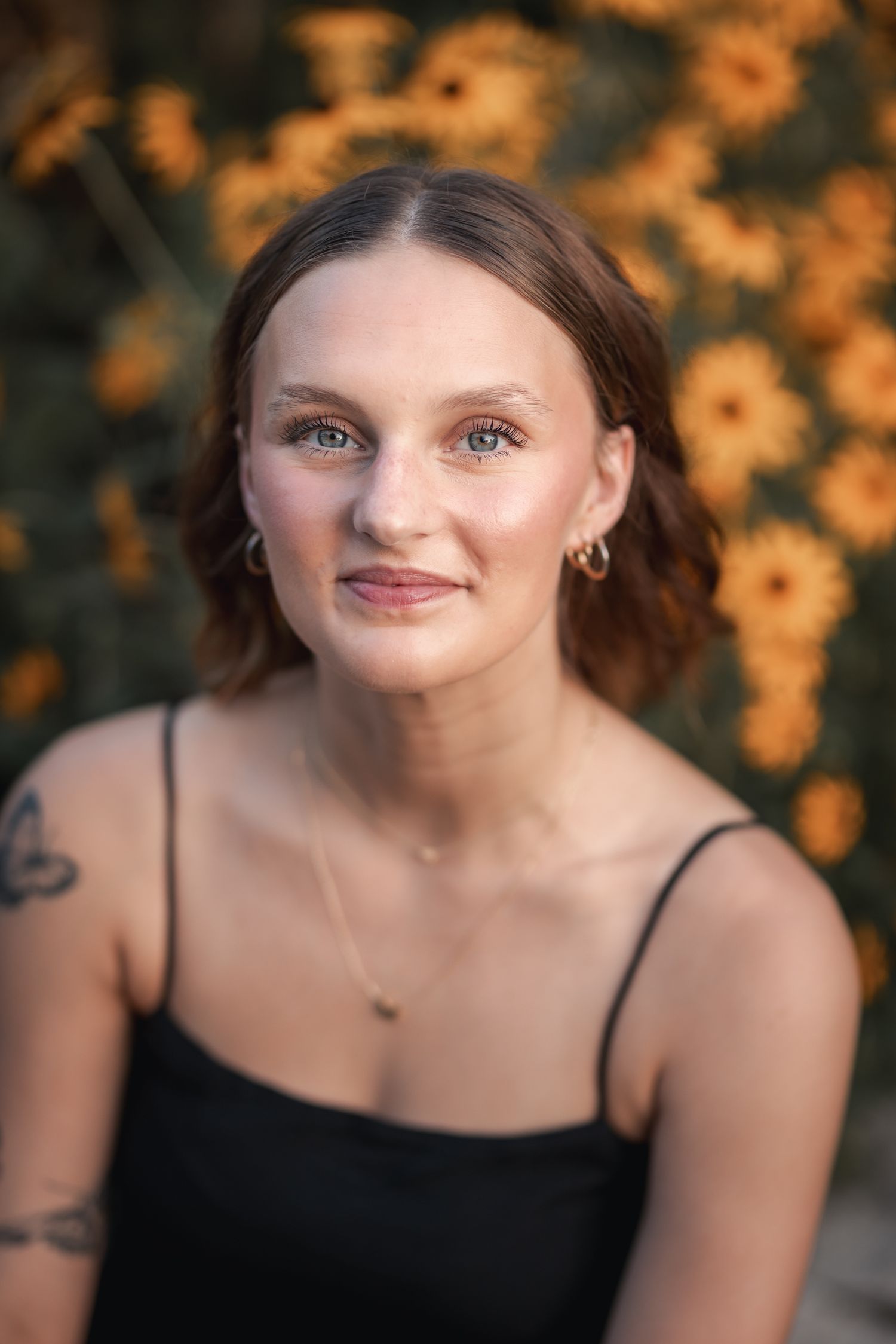 Portrait in front of orange flowers with soft natural lighting.