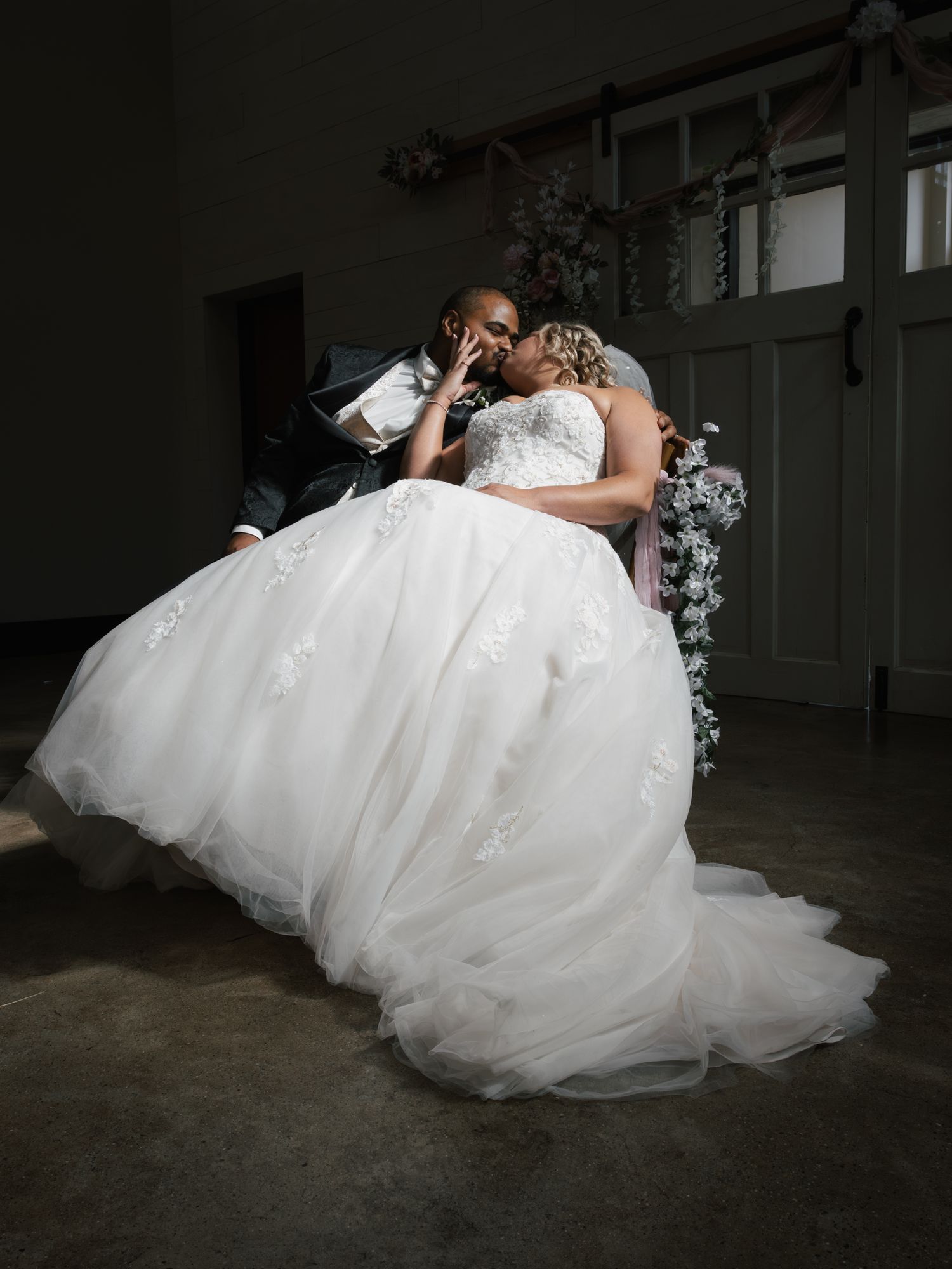 A wedding couple shares an intimate moment in an elegant ballroom setting.