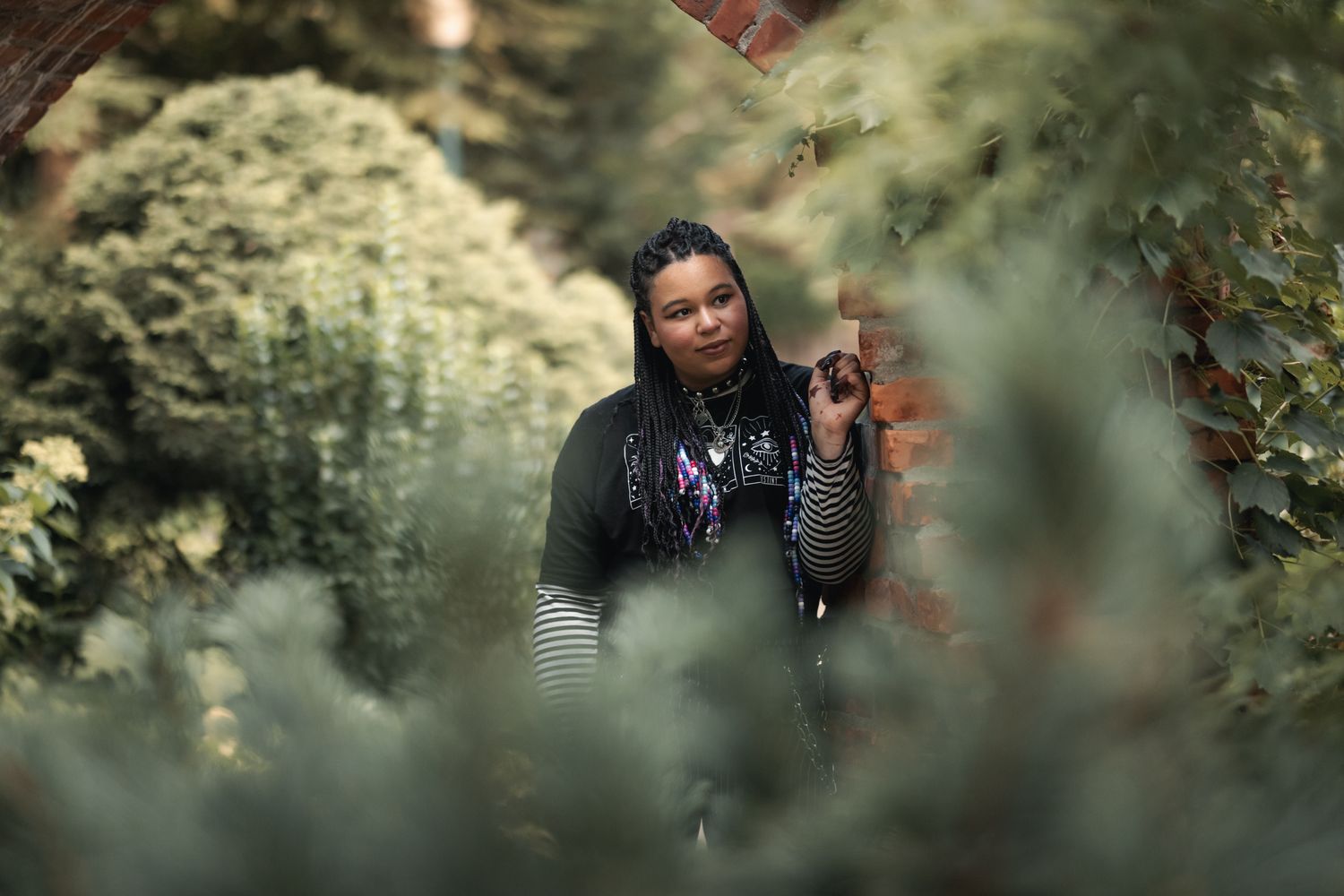 An artistic portrait through foliage of someone in natural lighting.