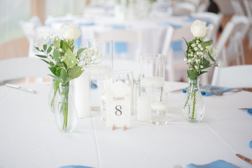 Elegant table settings with numbered cards and small floral centerpieces in glass vases.