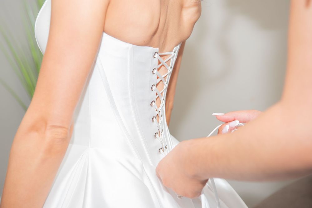 Detail shot of white corset-style wedding dress with satin lacing.