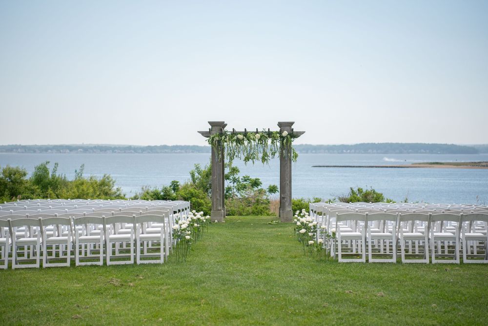 Waterfront wedding ceremony setup with white chairs overlooking the ocean.