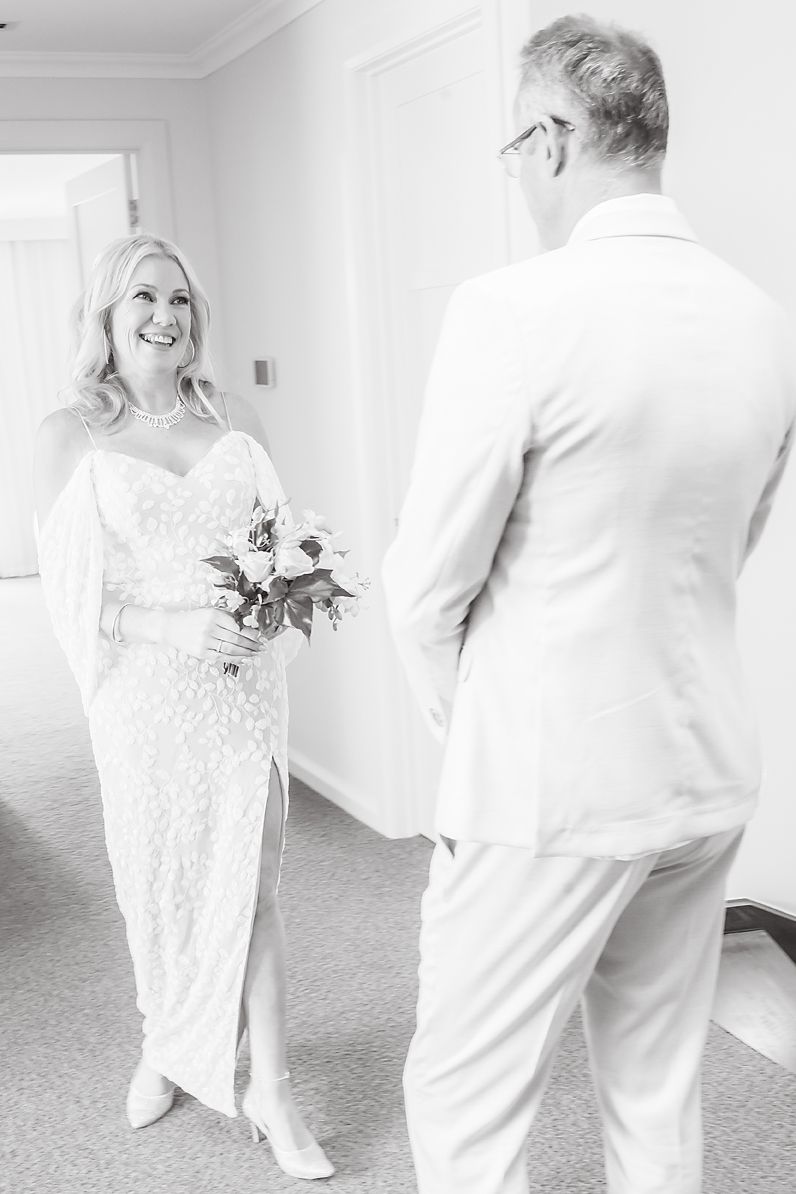 A joyful couple in wedding attire sharing a candid moment while dancing together in a bright indoor space.