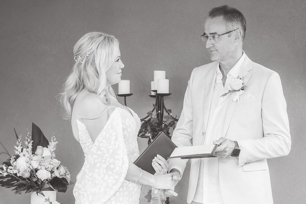 Black and white photo of a wedding ceremony with couple exchanging vows by candlelight.