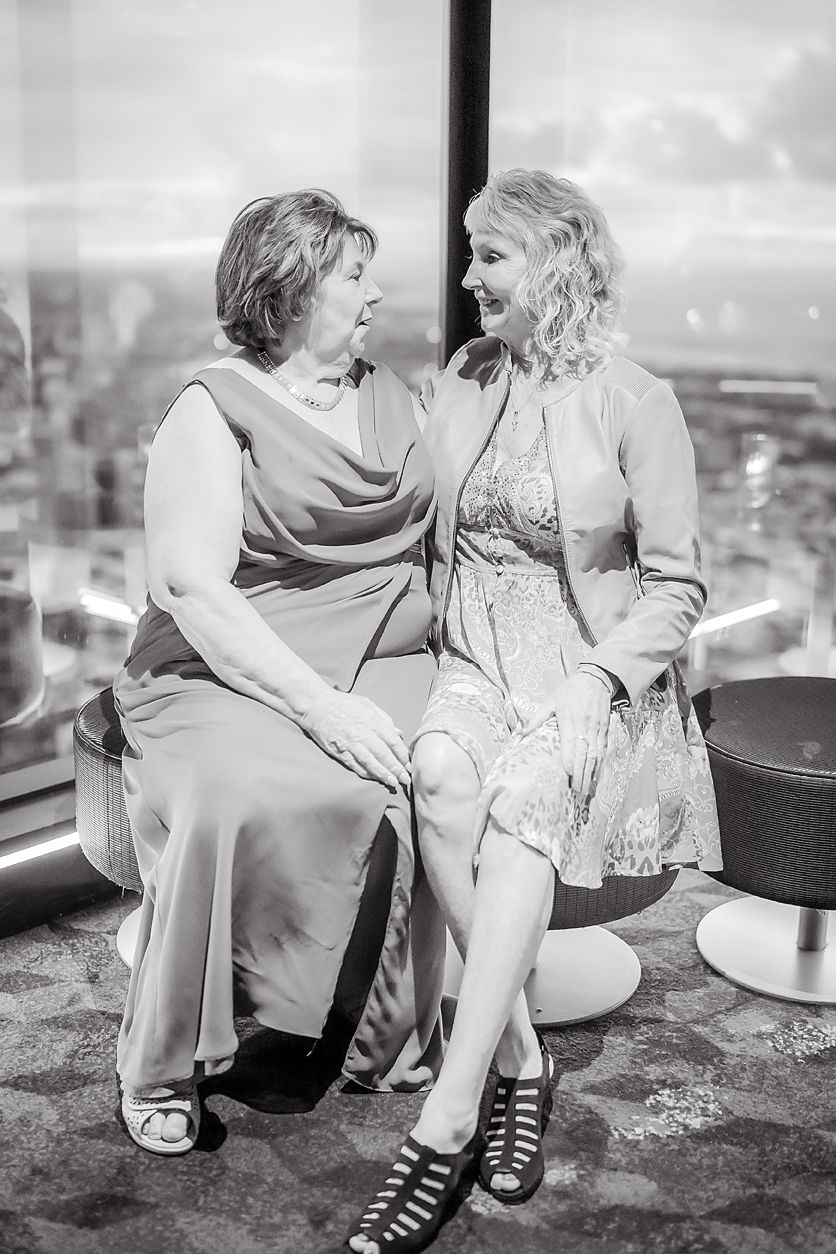 A romantic couple sits together on a rooftop overlooking a city in black and white photography.