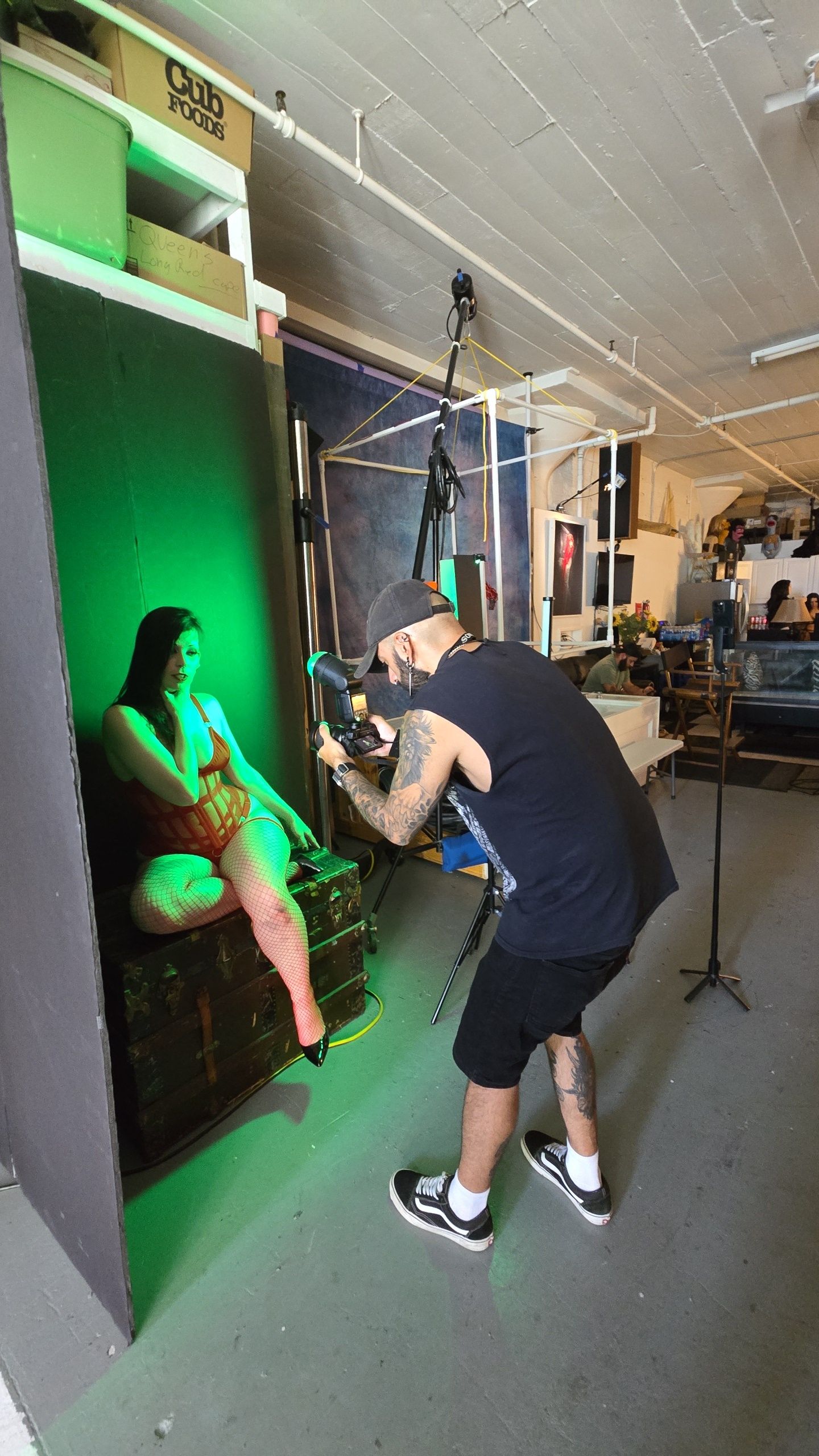 Behind-the-scenes photo shoot setup showing green lighting and photography equipment in a studio space.