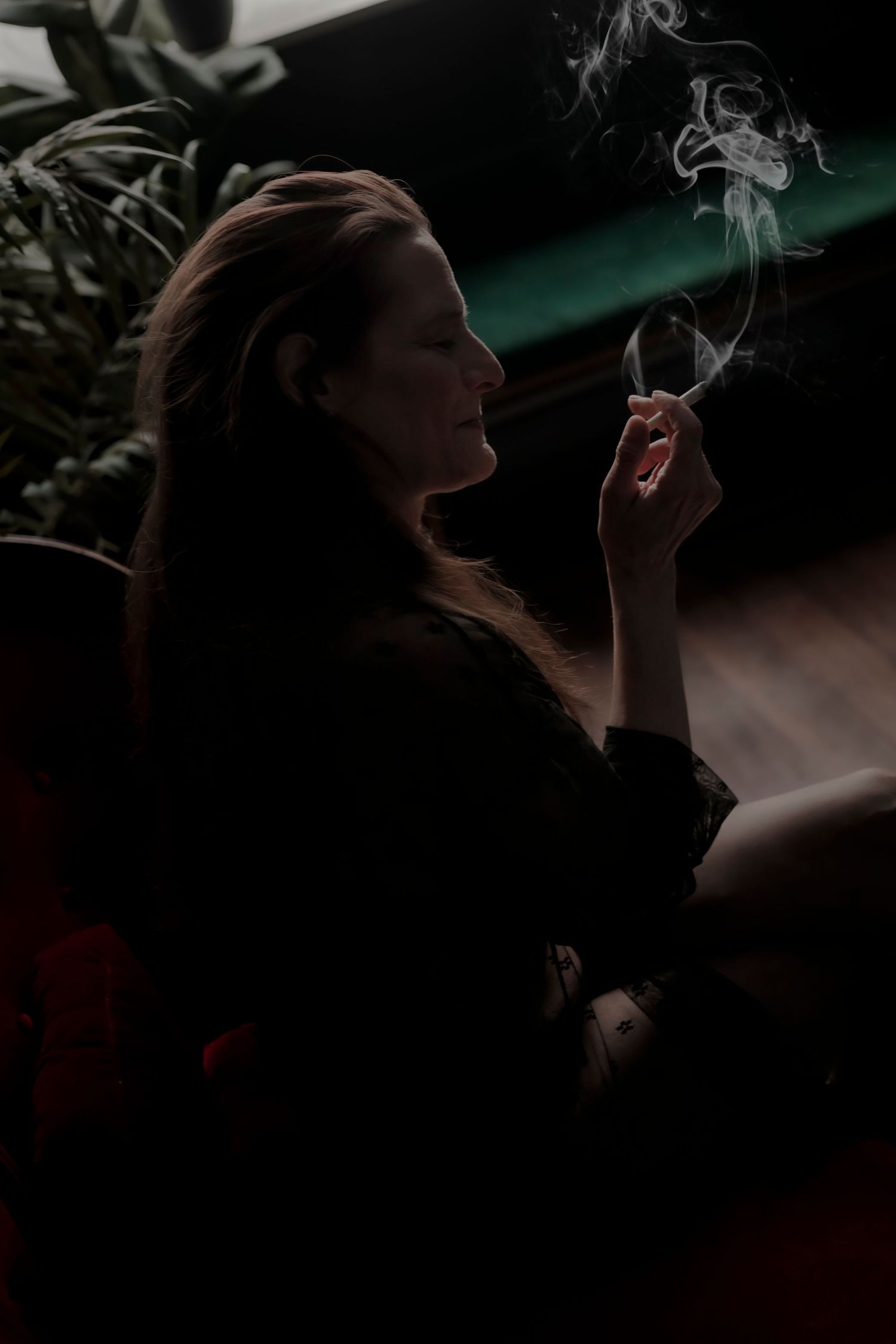 A figure lies on the floor in moody lighting with a decorated Christmas tree glowing in the dark background.