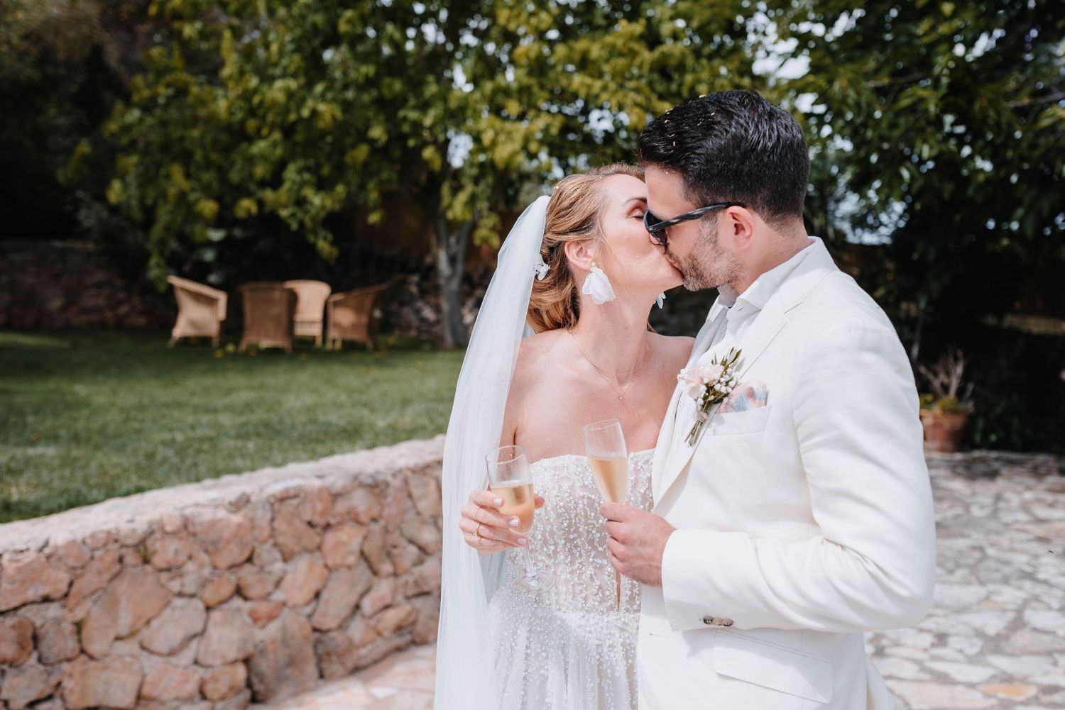 A happy couple shares a romantic moment together on their wedding day wearing elegant white attire outdoors.
