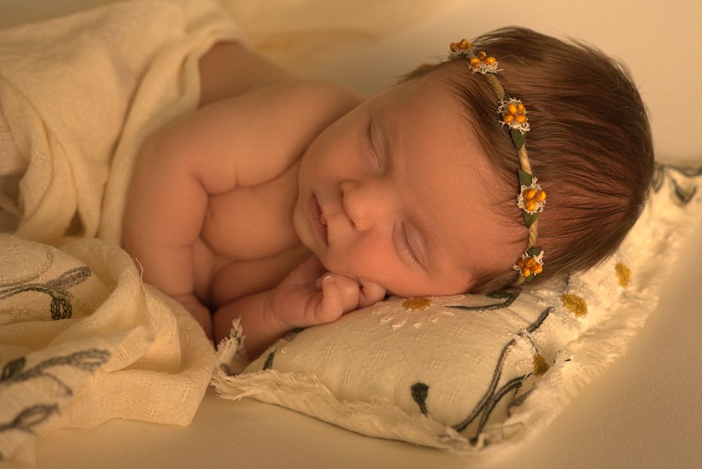 Sleeping newborn with crown photographed in warm tones.
