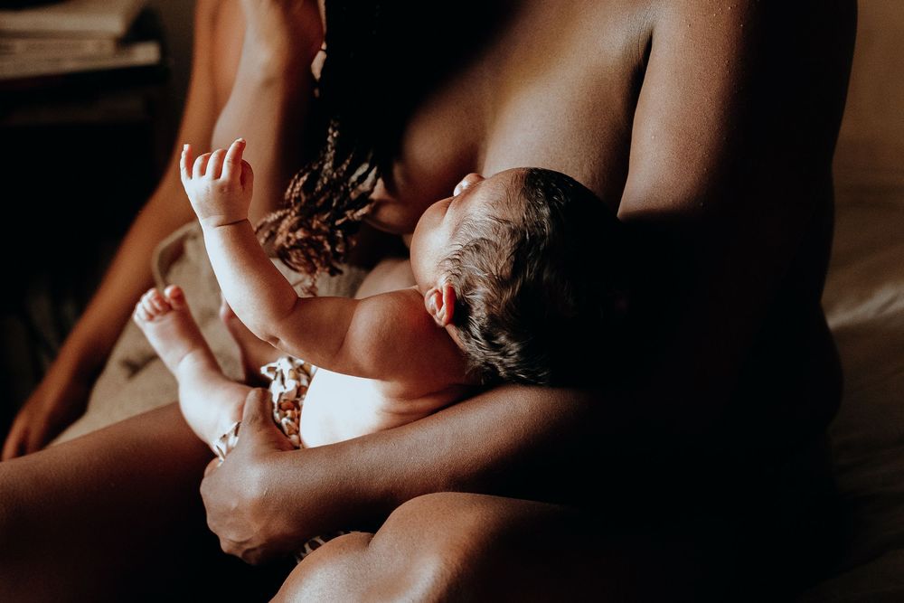 A newborn baby sleeps peacefully while being cradled in someone's arms during an intimate indoor photoshoot.