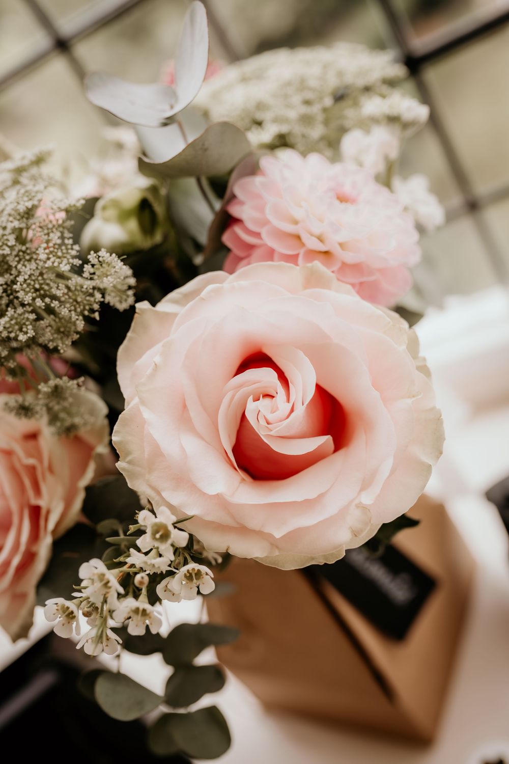 Close-up of a delicate pink rose bloom with soft petals in a romantic floral arrangement.
