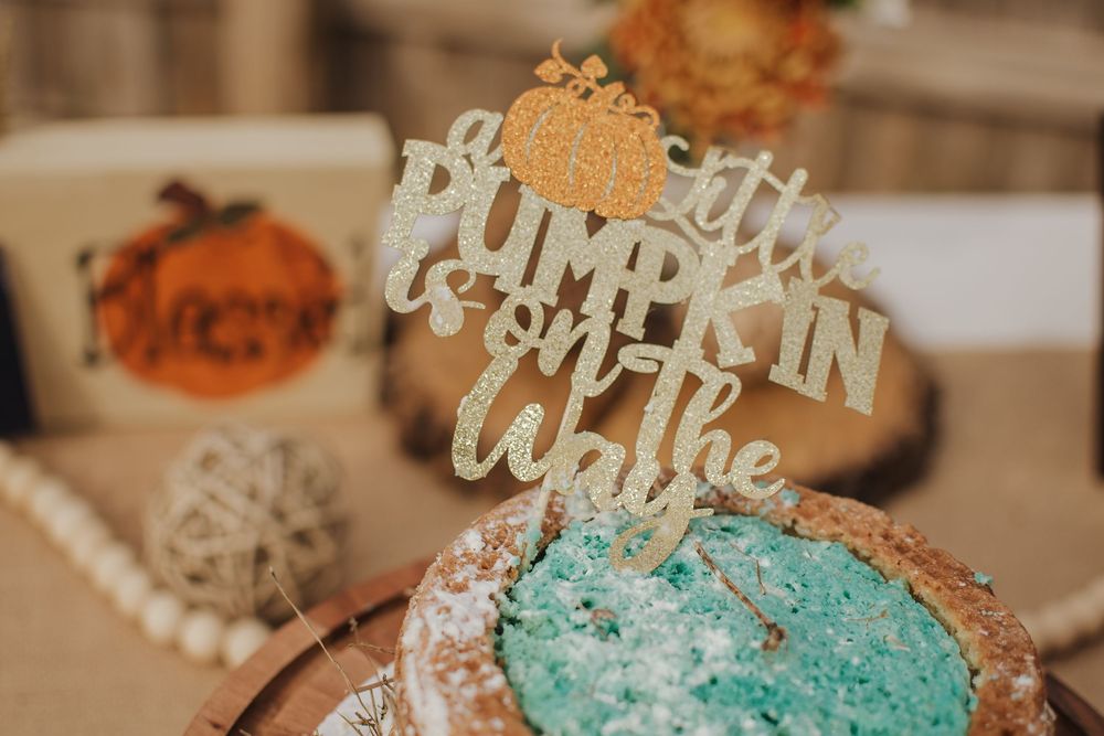A festive autumn cake with a gold 'Little Pumpkin' topper and teal frosting details.