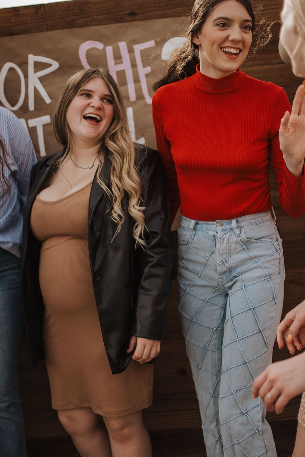 Two people laughing and enjoying a moment together against a wooden wall with text decorations.