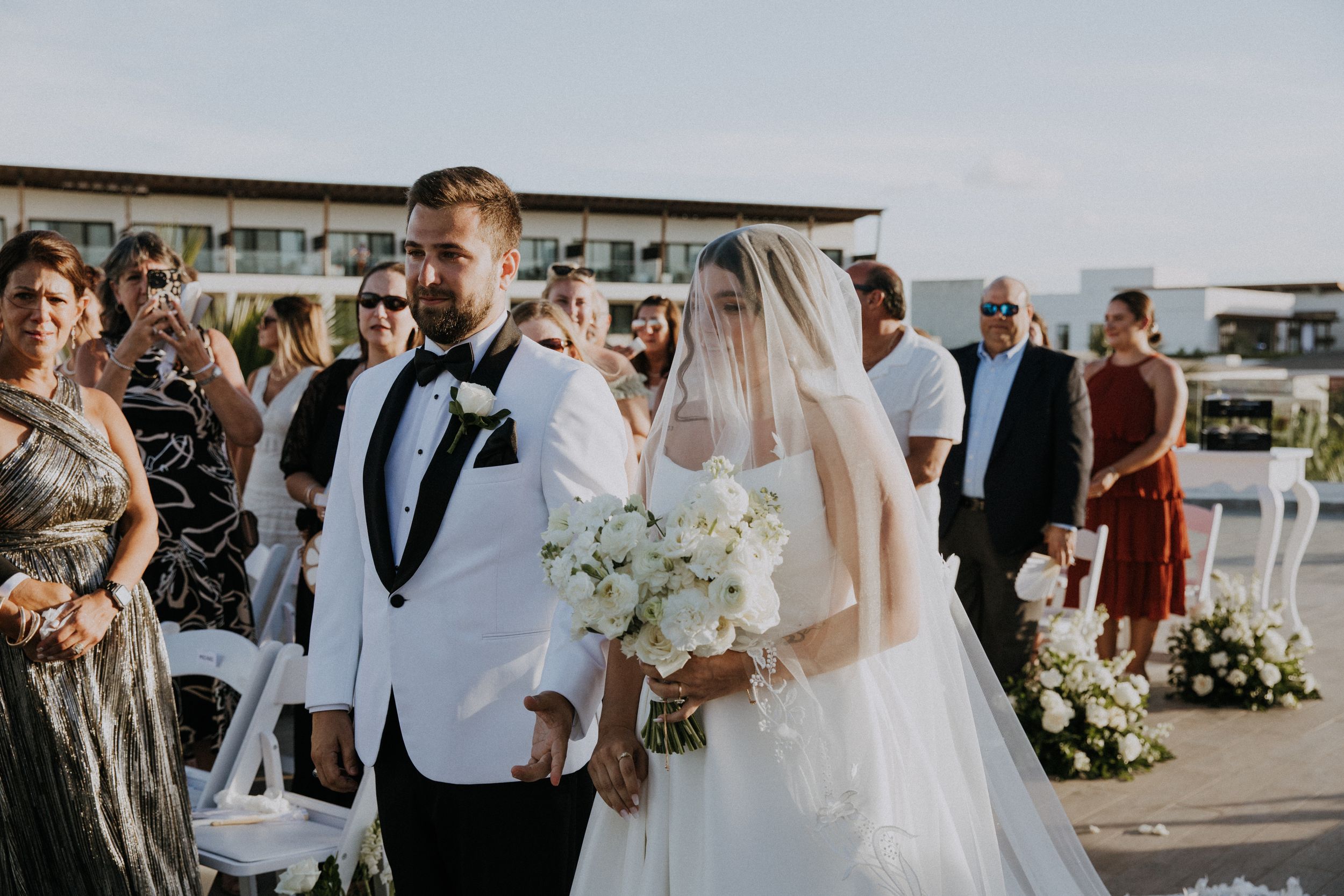 Elegant wedding ceremony moment at modern rooftop venue with white and greenery decor.