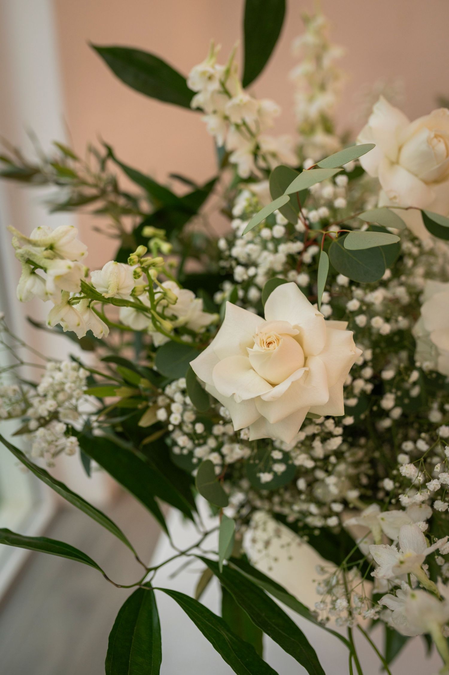 Elegant white and blush roses with baby's breath and greenery arranged in a romantic wedding floral display.