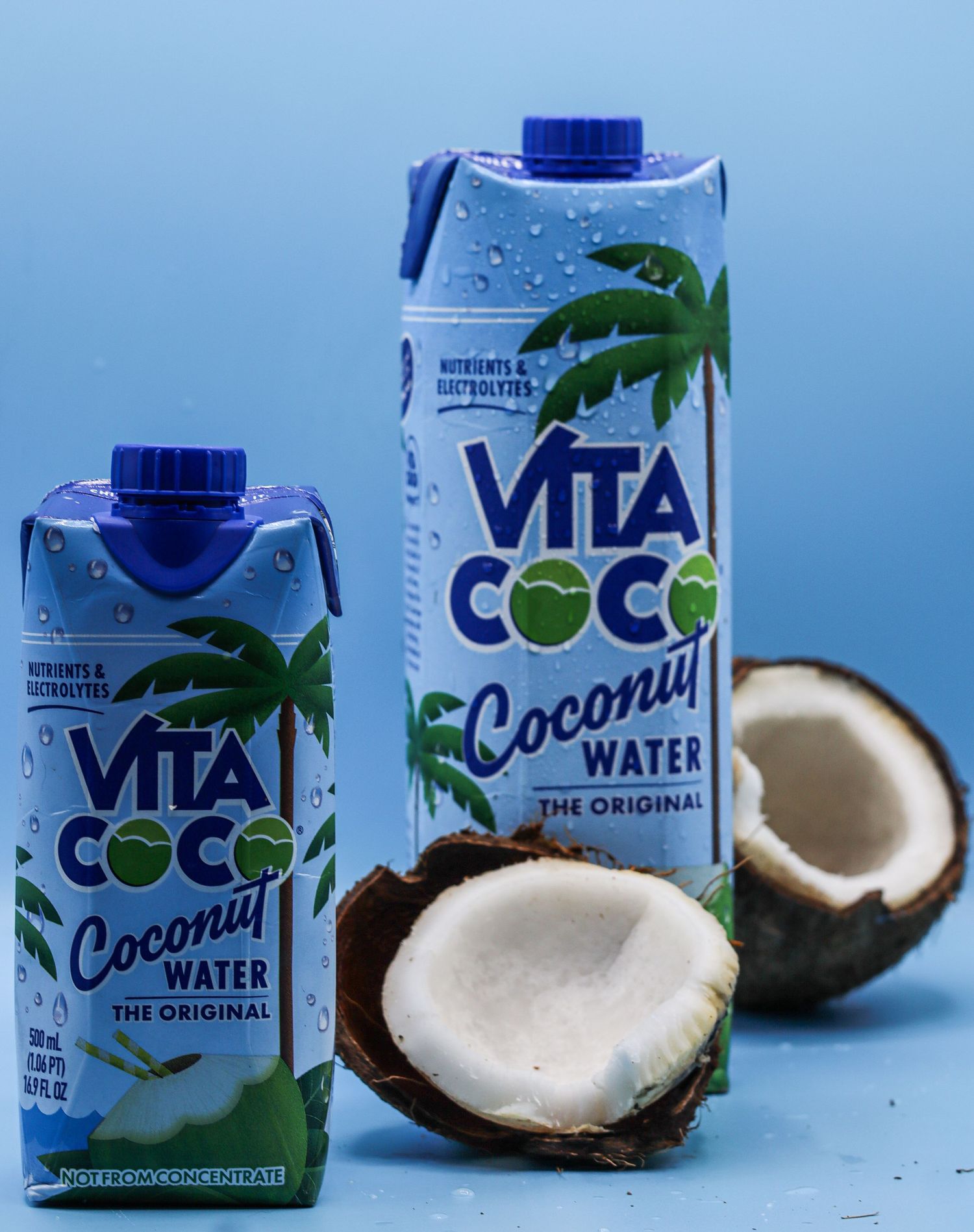 Fresh coconuts and packaged coconut water products lined up against a blue sky background show tropical beverage options.