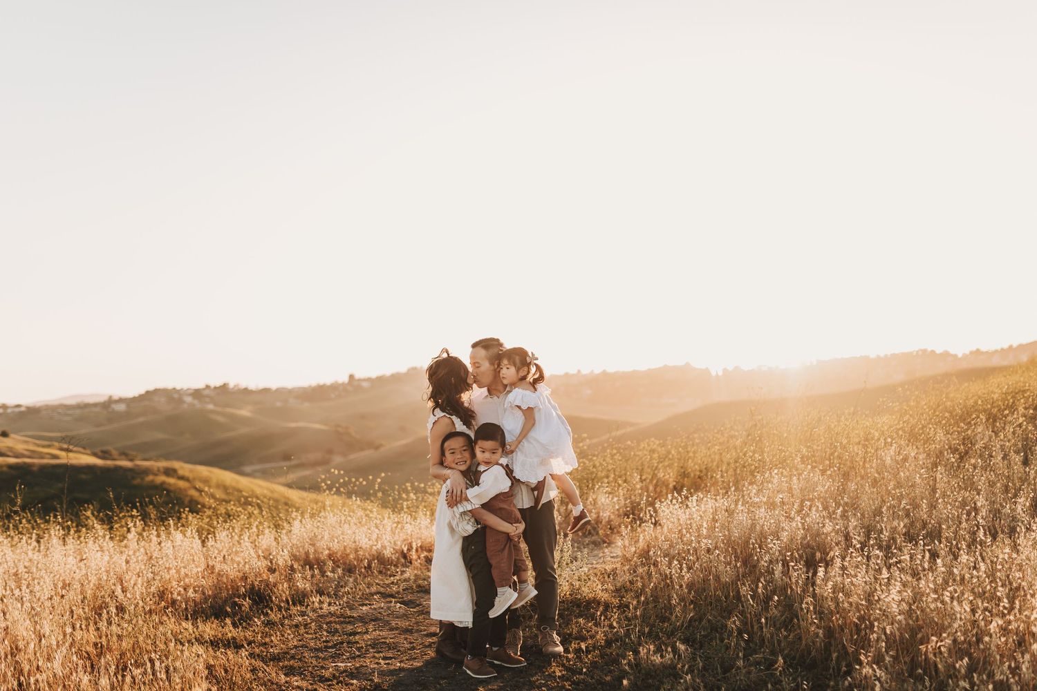 People embrace on scenic golden hill during sunset in beautiful mountain landscape.