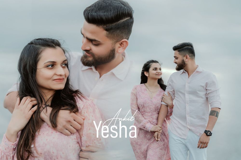 A romantic couple poses outdoors wearing coordinated pink and white outfits in a soft pastel photoshoot.