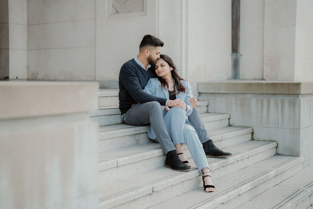 A person sits alone on white marble steps wearing blue jeans and sandals in a minimalist architectural setting.