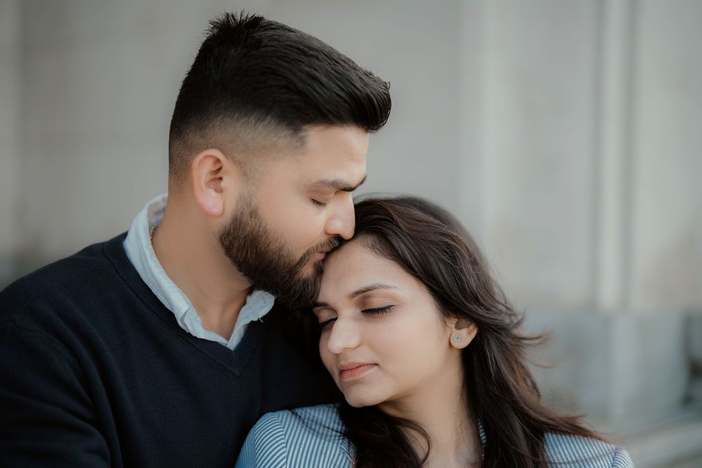A tender romantic moment between a couple embracing while leaning against a wall with soft lighting.