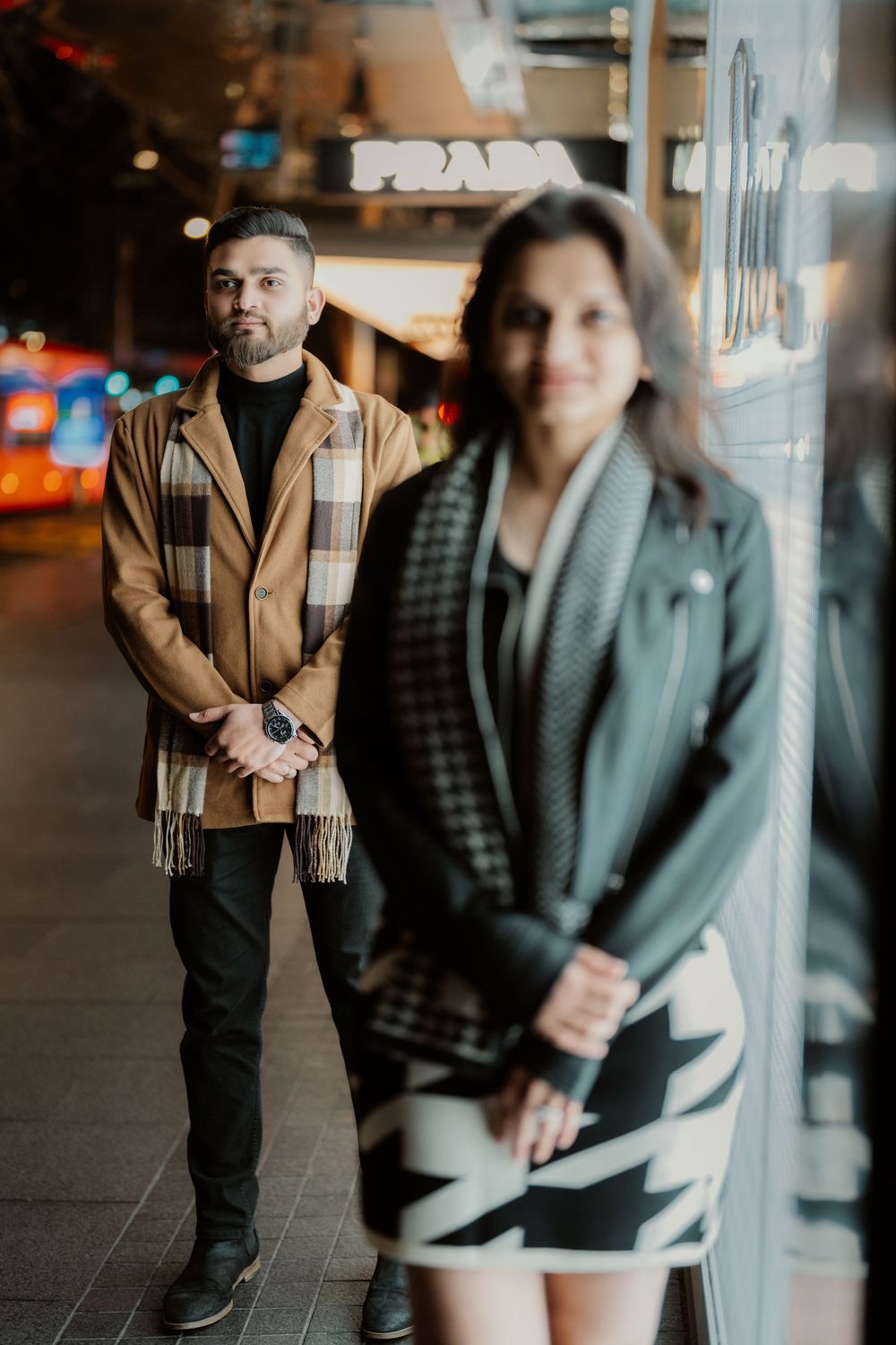 Couple poses together in a modern indoor setting with dramatic window lighting.