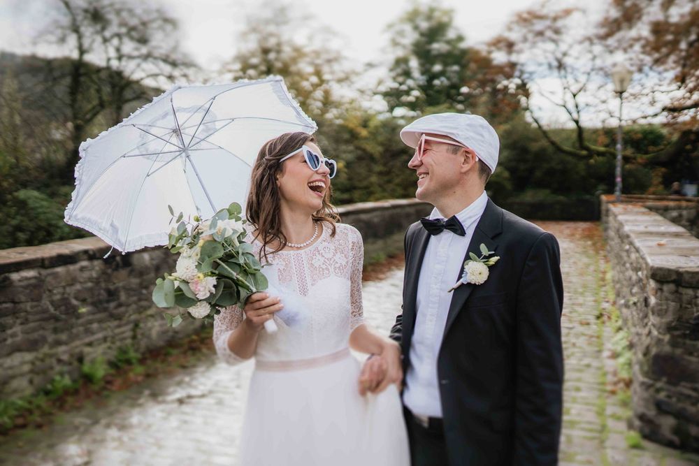 Couple with white umbrella share romantic moment on stone pathway.