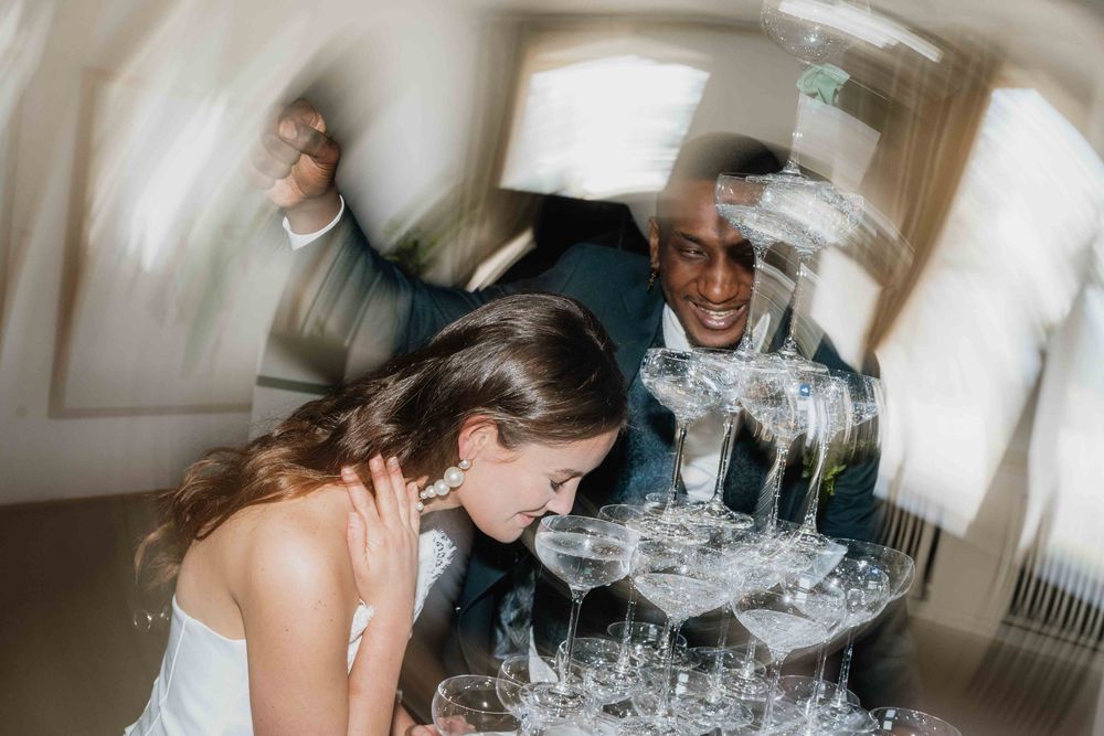 A sequence of photos showing a couple attempting to blow down a champagne glass tower.