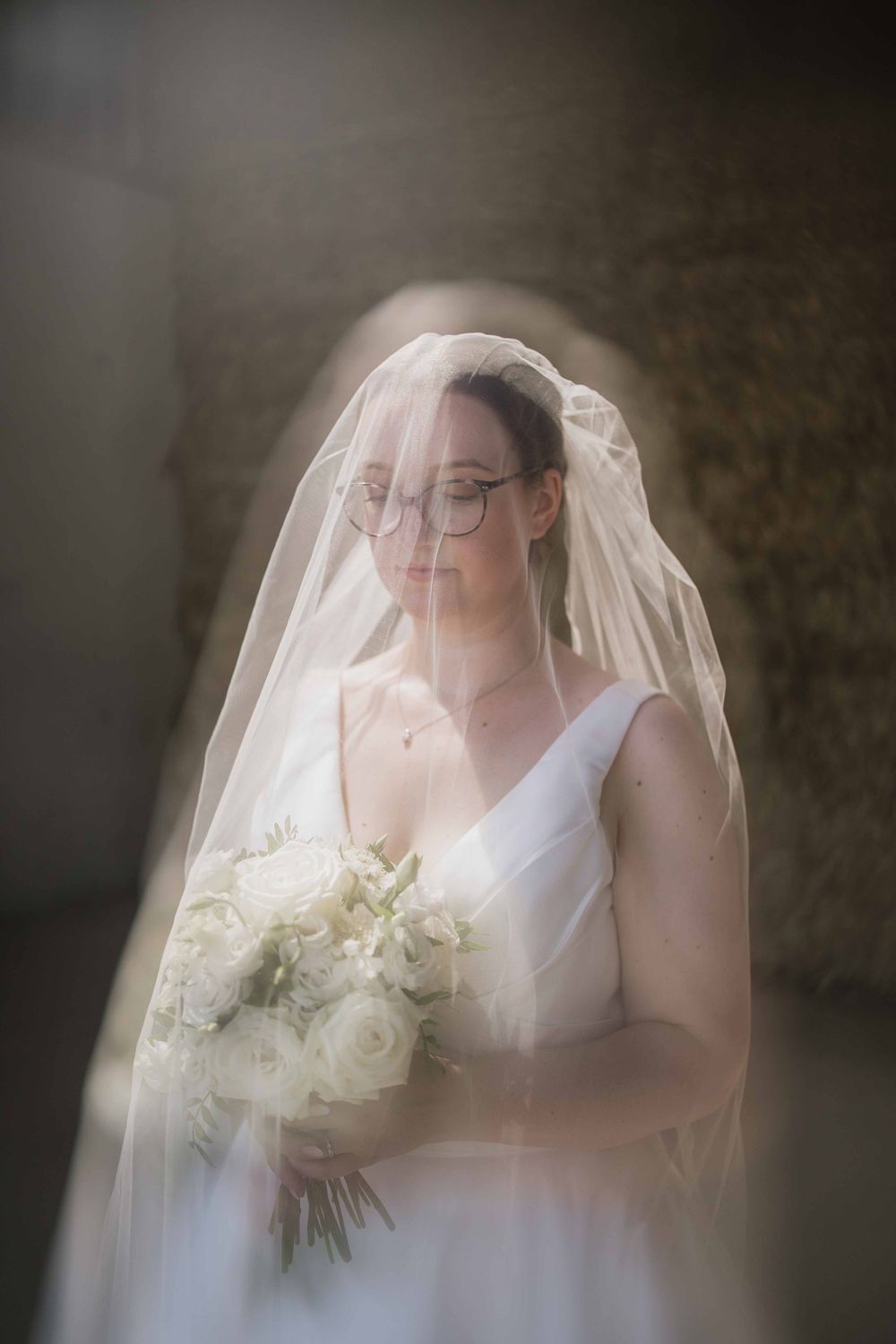 A dreamy wedding portrait showing a bride in a white dress holding a bouquet of white flowers.