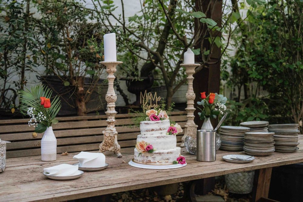 Rustic wedding cake display on wooden table with candlesticks and floral decorations.