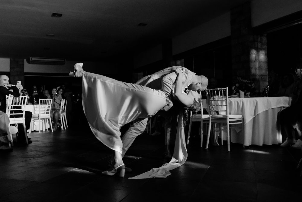 Black and white photo of bride and groom sharing a romantic dip dance at their wedding reception.