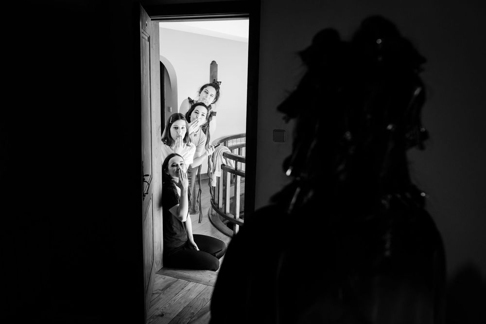 Dramatic black and white silhouette of wedding preparation through doorway.