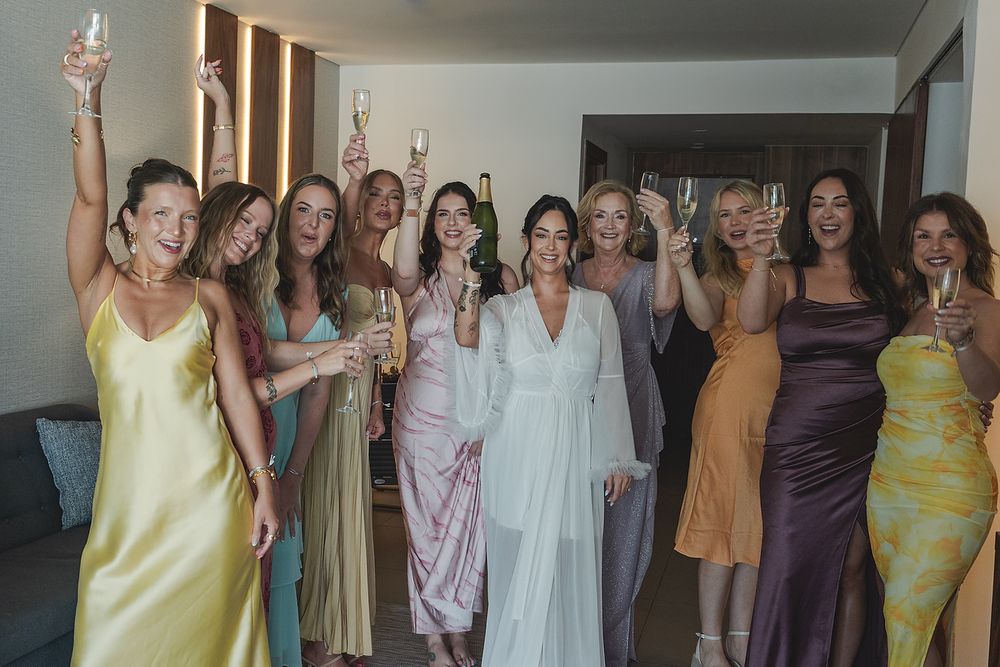 Bridesmaids in colorful dresses celebrating Majestic Elegance Costa Mujeres Riviera Maya wedding photographer.
