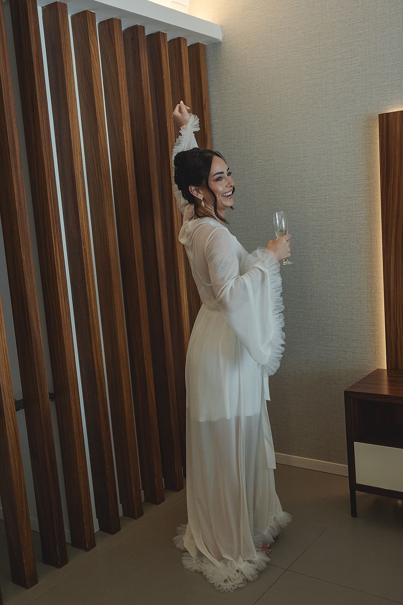 Bride in white gown holding a champagne glass and smiling at Majestic Elegance Costa Mujeres Riviera Maya wedding photography.