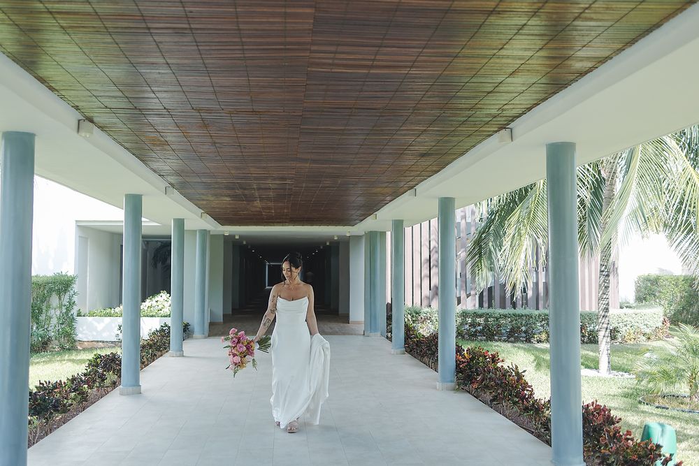 Covered outdoor colonnade with white pillars and wooden ceiling overlooking tropical landscaping.