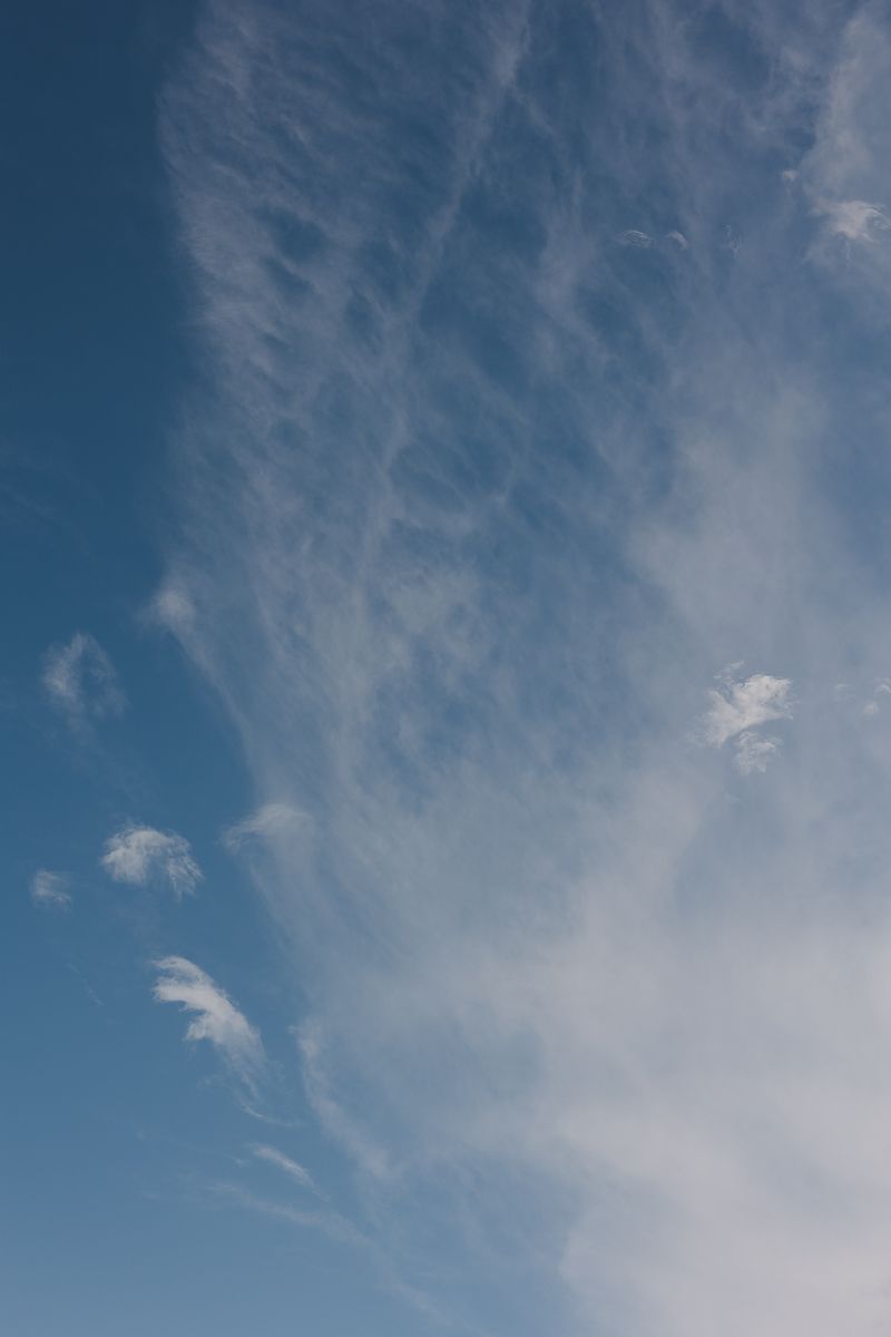 Wispy white cirrus clouds spread across a bright blue sky in a peaceful daytime scene.