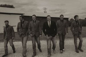 Black and white photo of a group walking together in casual suits outdoors.