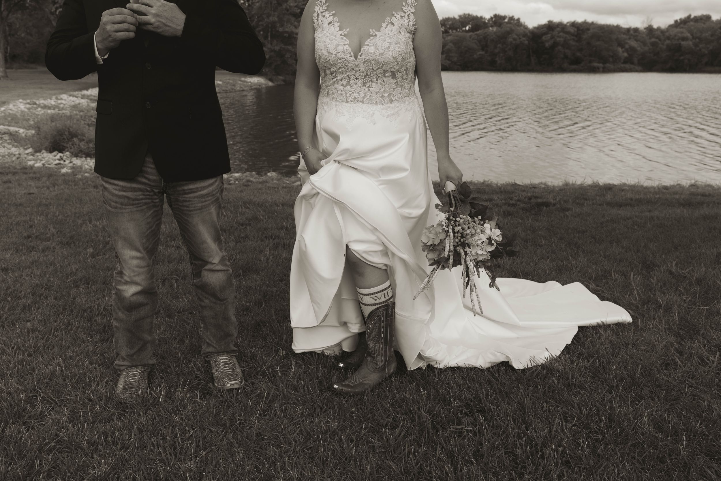 Black and white wedding photo showing cropped view of couple and guests outdoors.