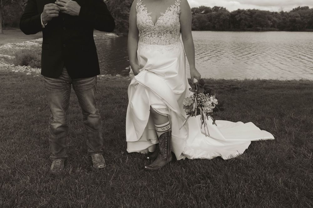 Black and white wedding photo showing cropped view of couple and guests outdoors.