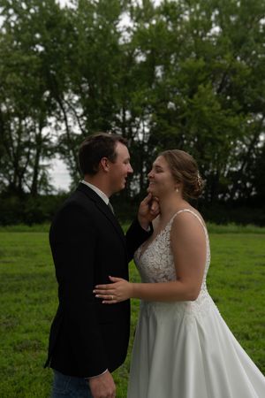 A couple shares an intimate first look moment in a green field during their wedding day.