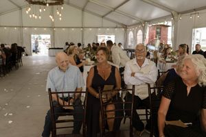 Wedding guests mingling inside a white tent decorated with string lights.