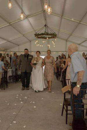 Wedding celebration in progress inside a white tent with guests dancing on concrete floor.