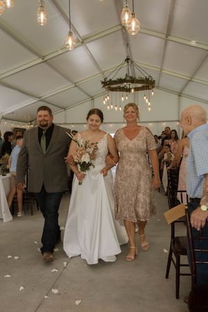 Wedding party members walking through a tent during reception celebrations.