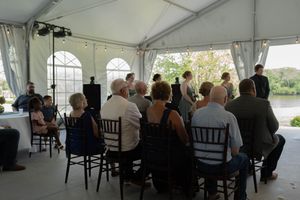 Wedding guests seated in black chairs during an indoor tent ceremony.