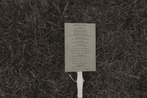 Wedding program or menu displayed on white stand against dark background.
