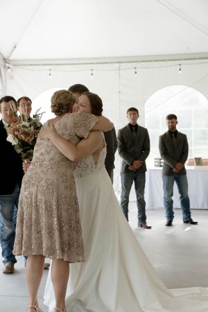 Emotional moments shared during a wedding celebration under a white tent venue.