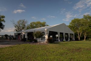 Panoramic view of a white wedding tent venue set up on grassy hillside.