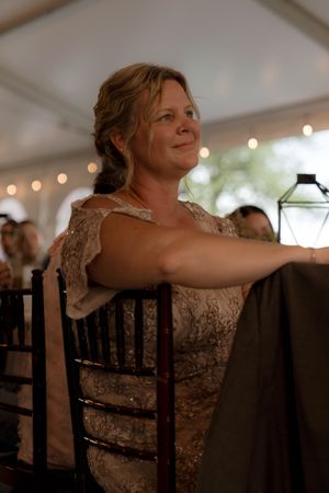 A guest in lace attire enjoying the wedding reception under string lights.