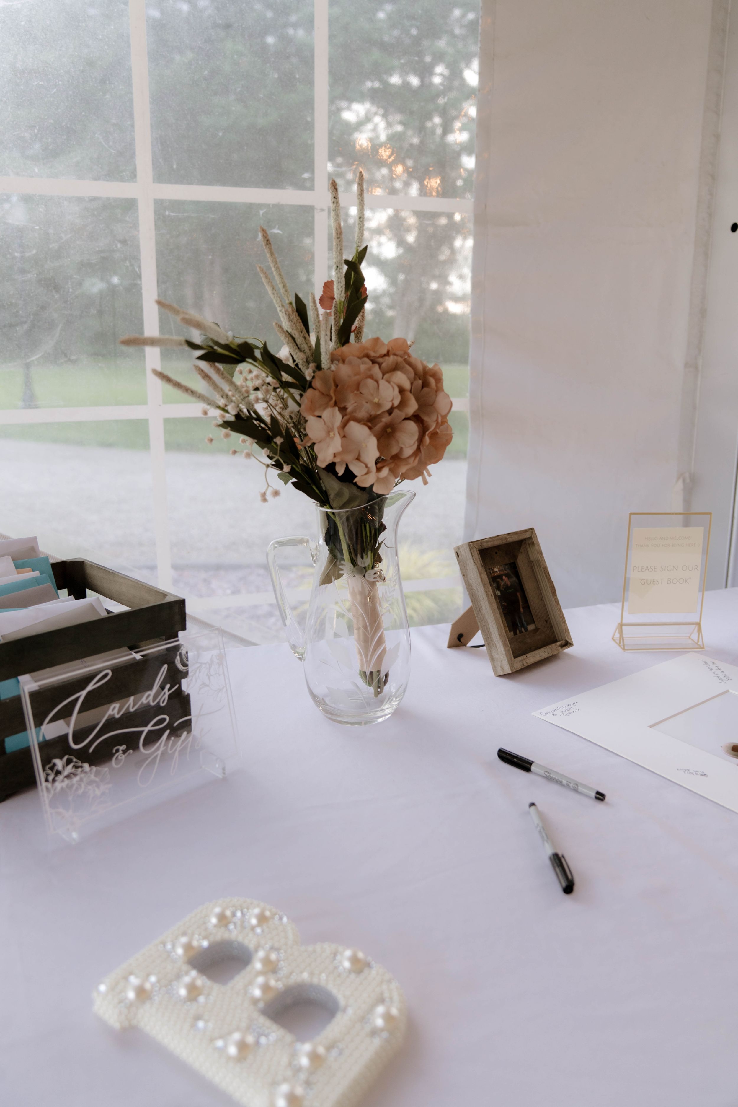 Wedding reception table with white tablecloth, floral arrangements and pearl heart decoration.